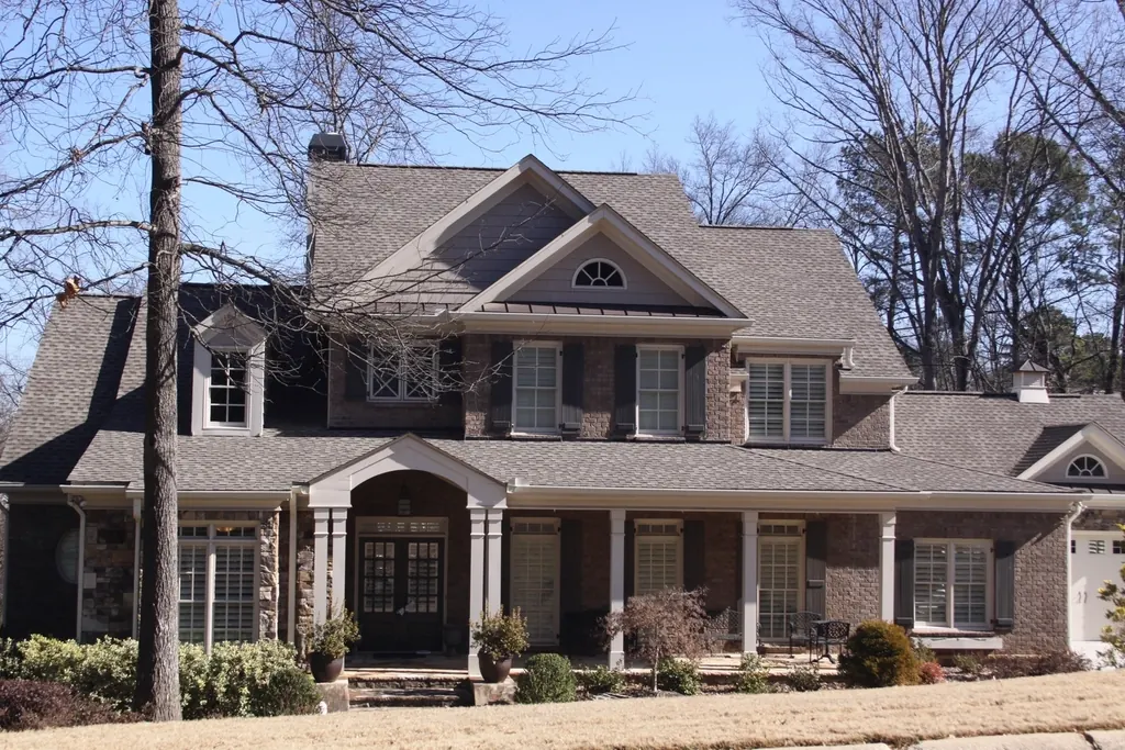 Two-story American home with a shingle roof, dormers and a covered front porch